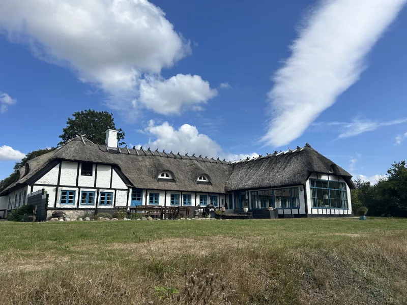 Stråtækt kursussted med blå vinduer under en sommerhimmel